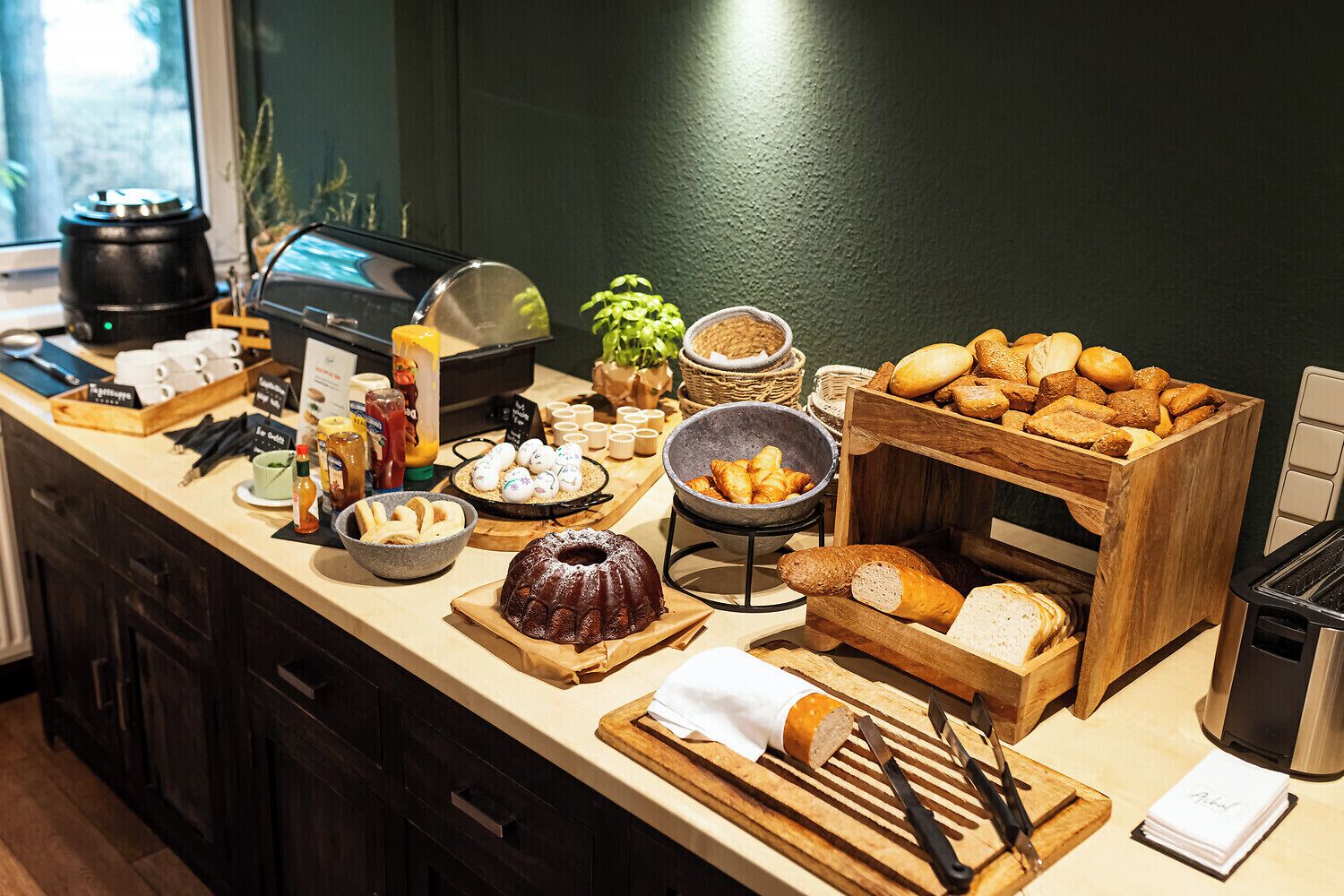 Ein Frühstücksbuffet mit verschiedenen Brotsorten, Gebäck und Beilagen.