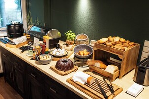Un bufé de desayuno con panes, pasteles y salsas diversas.