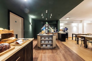 Una barra de desayuno con diversos pasteles y una estación de café en una habitación de hotel.