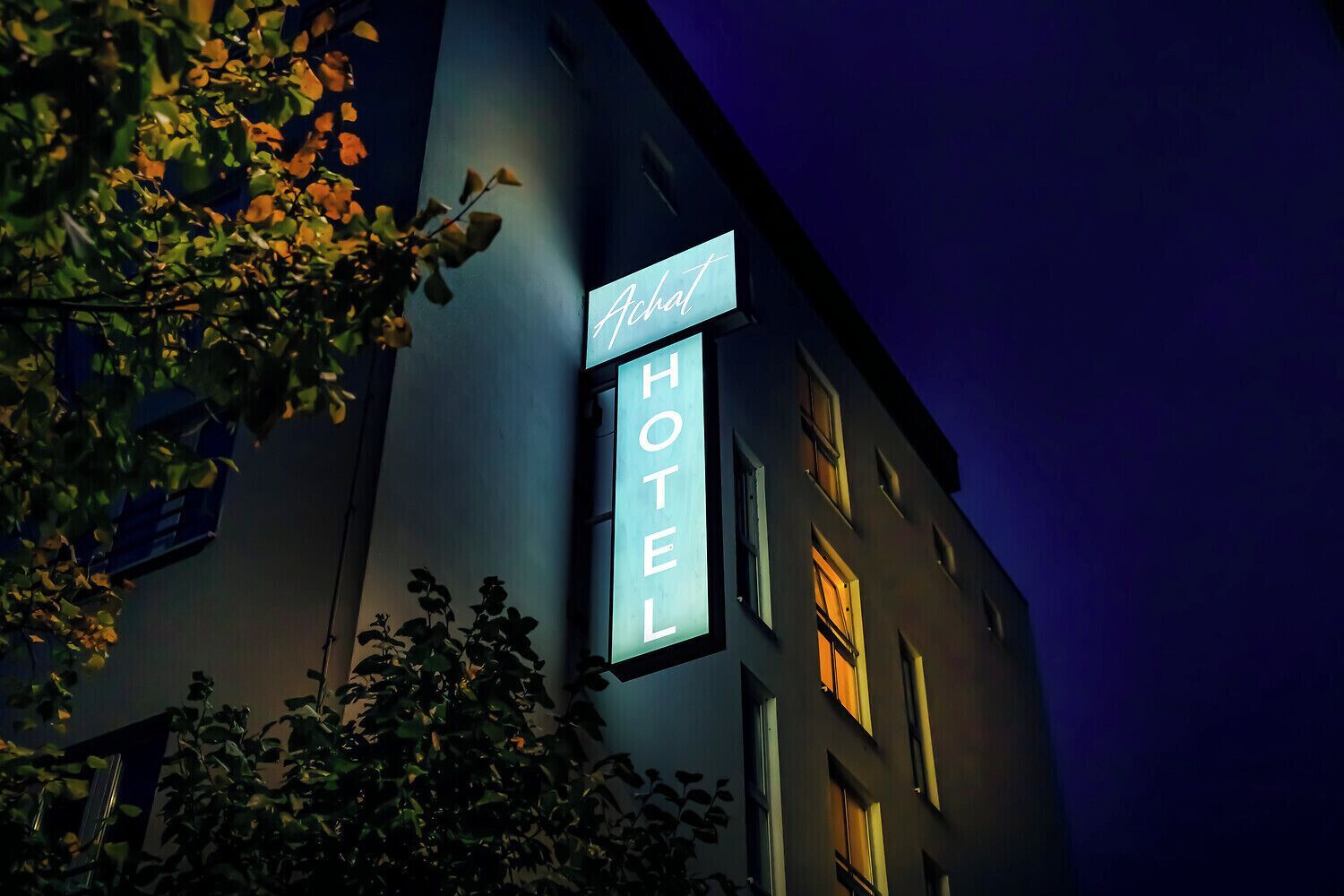 Ein Hotelschild, auf dem das Wort 'Hotel' in weißer Schrift auf dunklem Grund leuchtet.