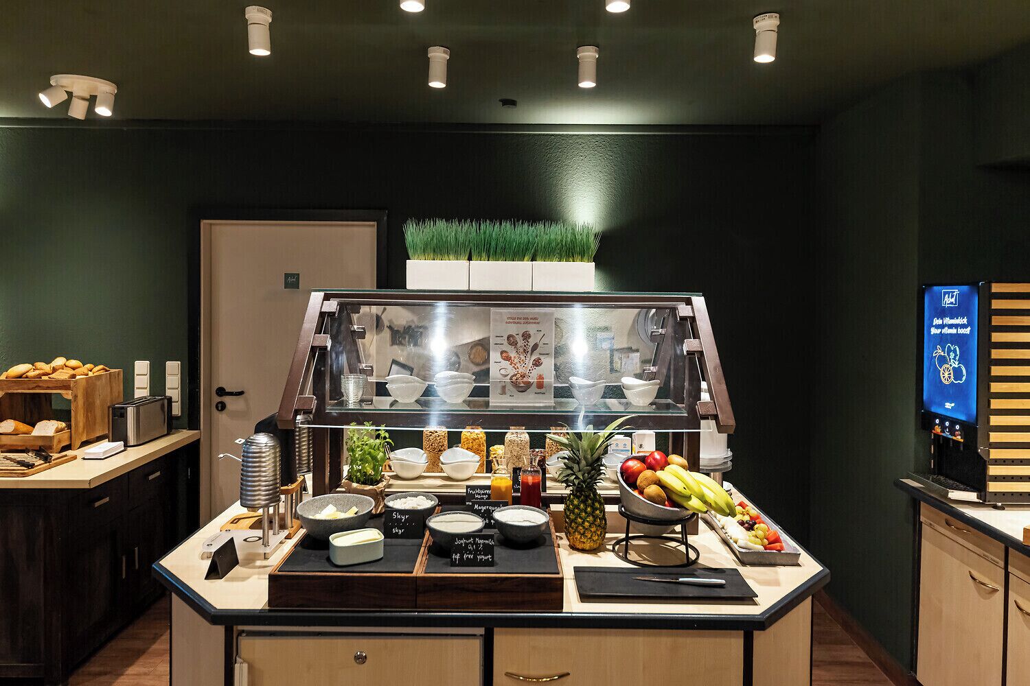 A breakfast bar with a variety of food items, a coffee machine, and a digital menu display.