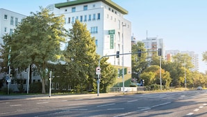 A multi-story hotel with a green roof and white facade, located at a city intersection. - ACHAT Hotel Darmstadt Griesheim (Griesheim)
