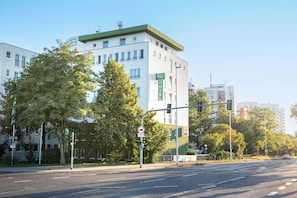 A multi-story hotel with a green roof and white facade, located at a city intersection. - ACHAT Hotel Darmstadt Griesheim (Griesheim)