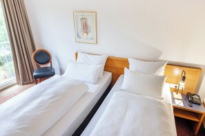 A hotel room with two beds, a chair, a bedside table with a lamp, and a painting on the wall. - ACHAT Hotel Darmstadt Griesheim (Griesheim)