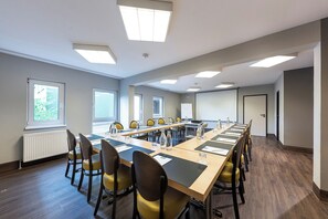 A conference room with a long table, chairs, and a projector screen. - ACHAT Hotel Darmstadt Griesheim (Griesheim)