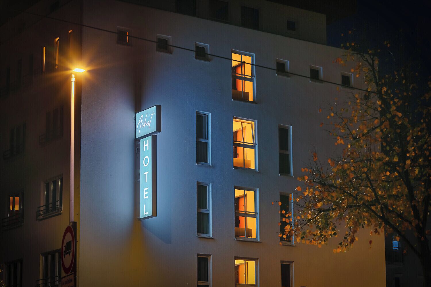 A hotel building with a sign that reads 'HOTEL' and multiple windows with illuminated interiors.