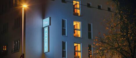 Un edificio de hotel con un letrero que dice 'HOTEL' y varias ventanas con interiores iluminados.