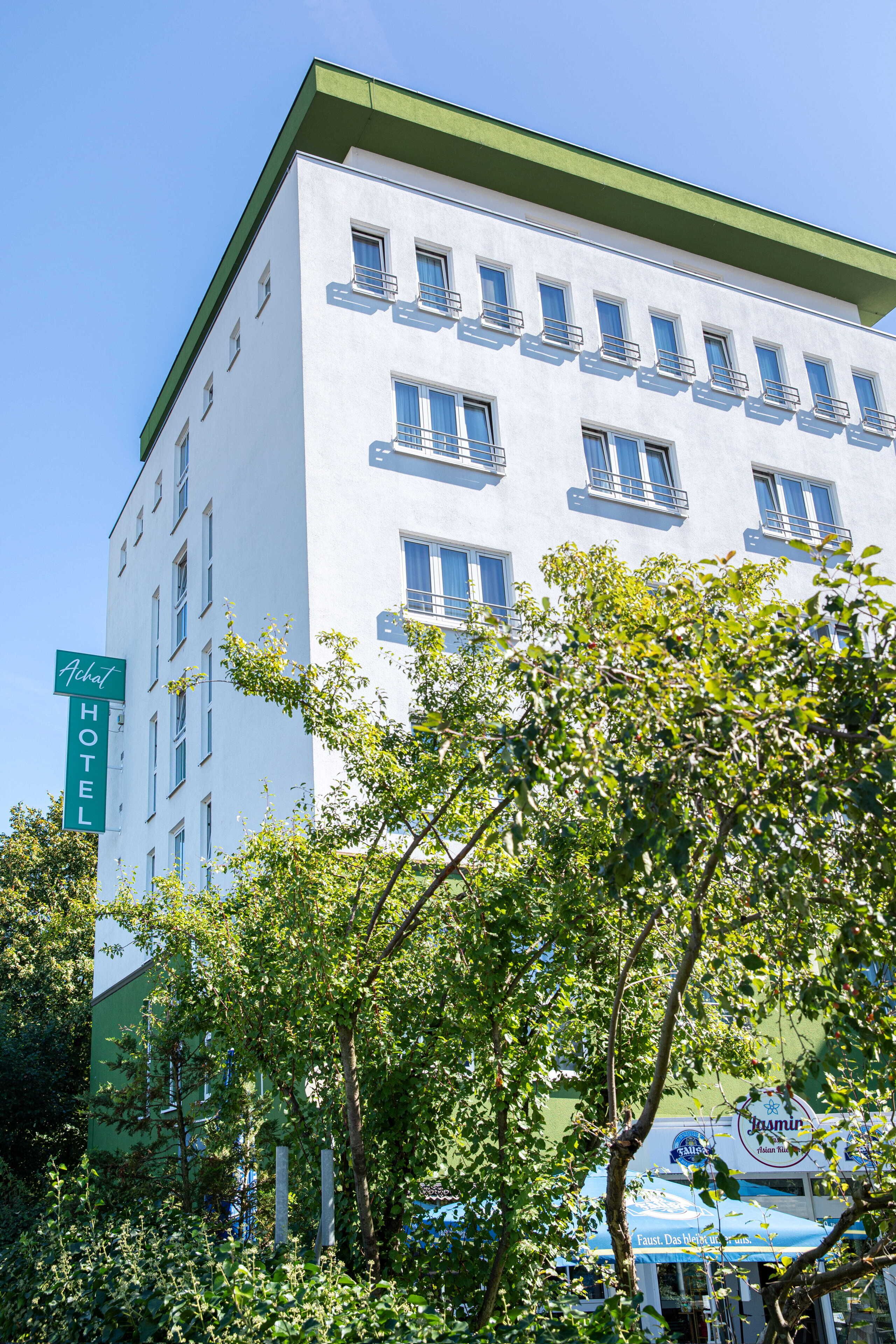 Ein mehrstöckiges Hotel mit einer grün-weißen Fassade, zahlreichen Fenstern und einem Schild, das es als Hotel kennzeichnet.