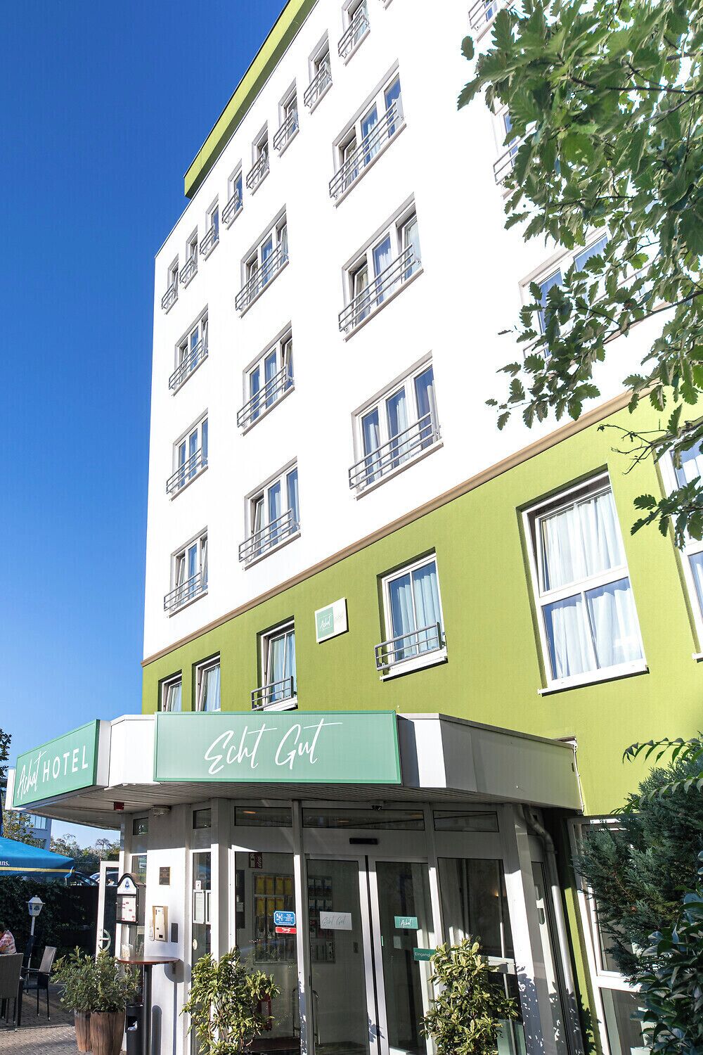 A hotel with a green facade and multiple windows.