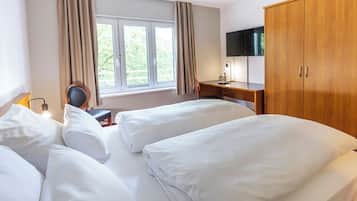 Habitación de hotel con dos camas, un escritorio, una silla, un televisor y un armario.