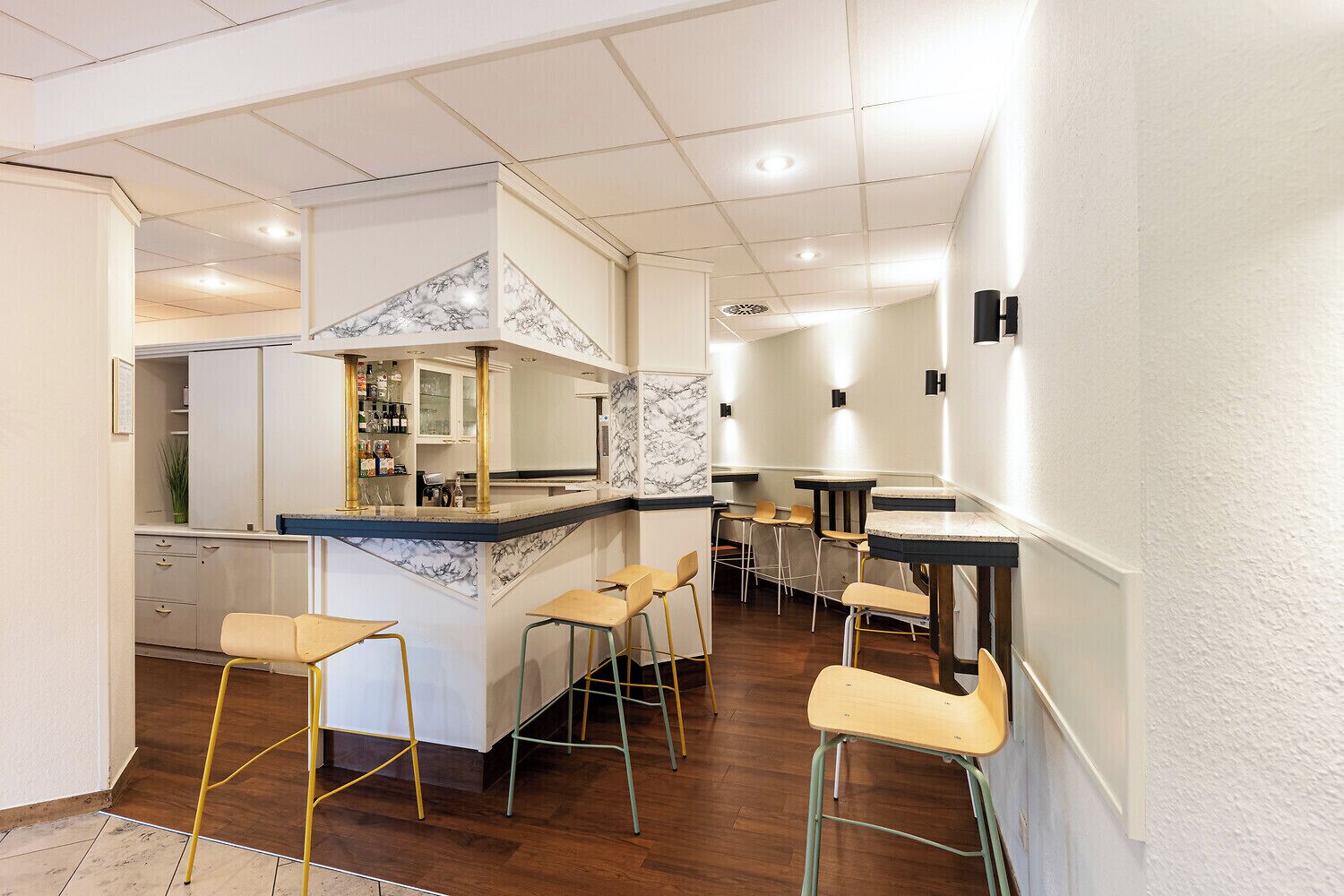 Una cocina con salpicadero de mármol, taburetes de bar y una isla central.