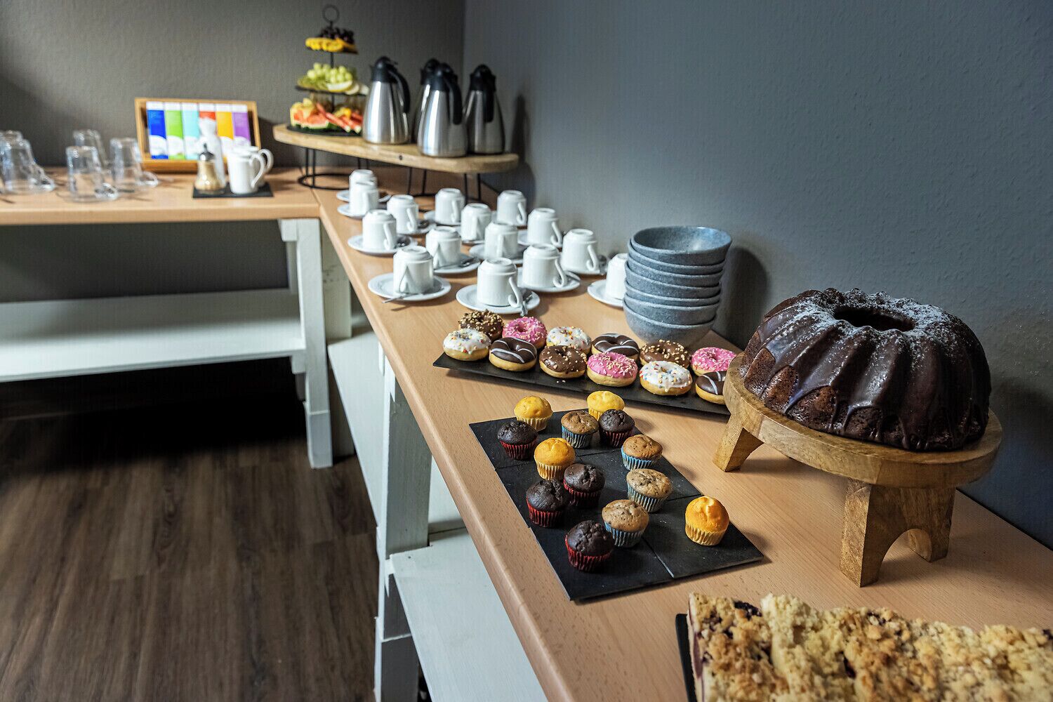 A breakfast buffet with various pastries, a chocolate bundt cake, and coffee and tea service.