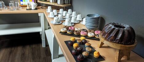 A breakfast buffet with various pastries, a chocolate bundt cake, and coffee and tea service.