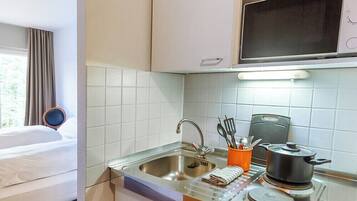 A compact hotel kitchen with a sink, stove, and a Siemens refrigerator.