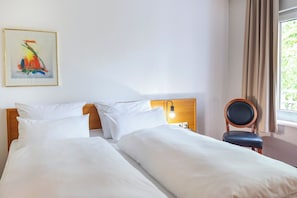 A hotel room with two beds, a nightstand with a lamp, a chair, and a painting on the wall. - ACHAT Hotel Darmstadt Griesheim (Griesheim)