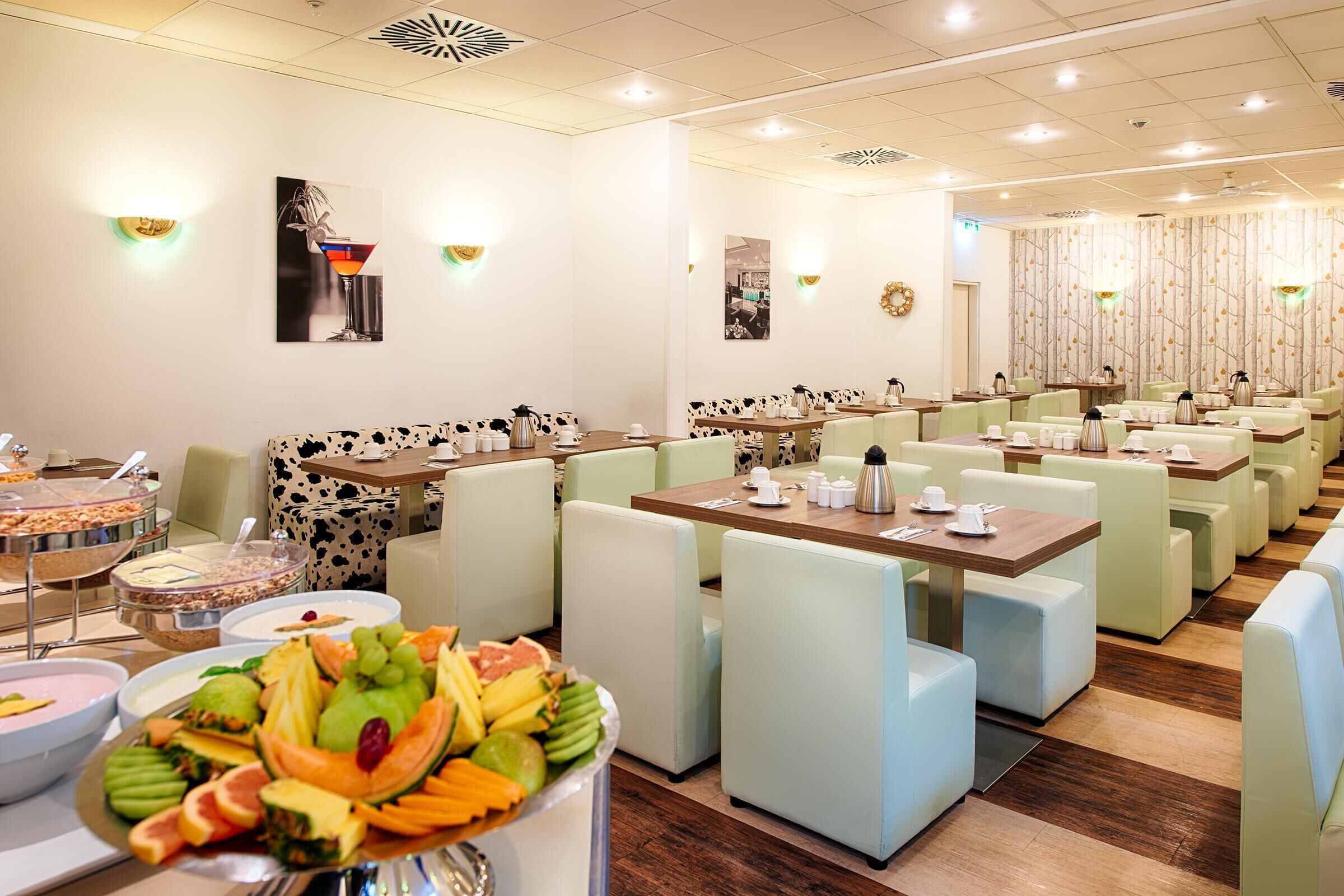 Un espace repas moderne, doté de banquettes et de tables, ainsi que de machines à café et de services à thé.