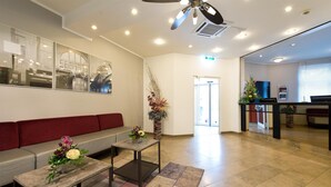A reception area with a sofa, a coffee table, and a vase of flowers. - ACHAT Hotel Frankenthal in der Pfalz (Frankenthal)