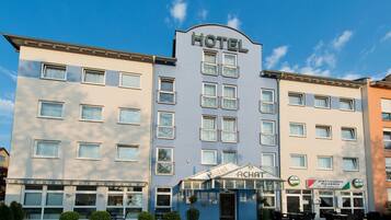 Ein Hotel mit einem großen 'HOTEL'-Schild, einem Restaurant namens 'RISTORANTE La Taverna' und einem Eingang mit der Bezeichnung 'Hotel ACHAT'.
