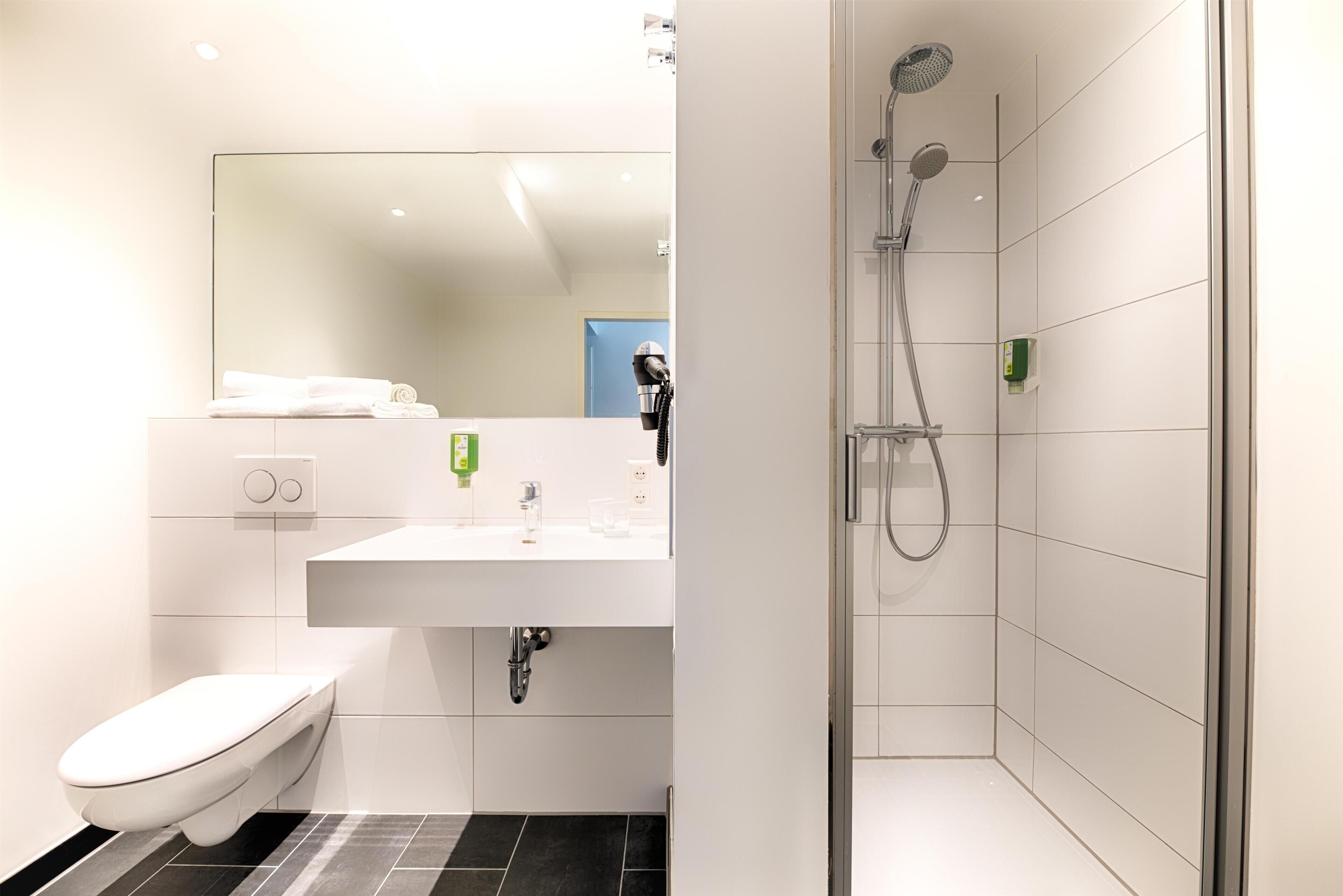 A modern bathroom with a toilet, sink, and shower.
