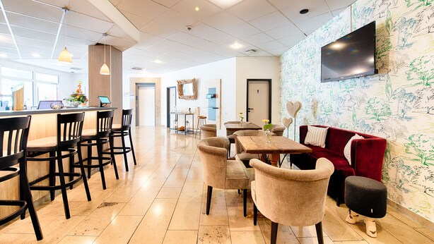 Un restaurante moderno con barra, asientos y un televisor en la pared.