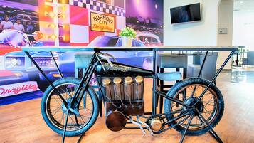 A drag racing car displayed in a showroom with a drag strip mural in the background.