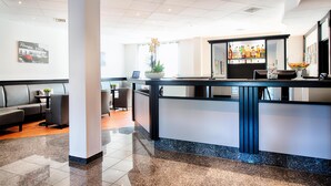 Un moderno vestíbulo de hotel con mostrador de recepción, zona de estar y bar.
