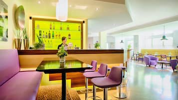 A modern hotel lobby with a bar area, seating arrangements, and a reception desk.