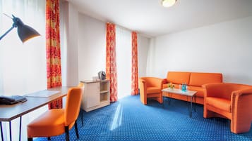 Habitació amb un terrablau dafadejat, mobles taronja, un escriptori amb una làmpada i una taula petita amb un ram.