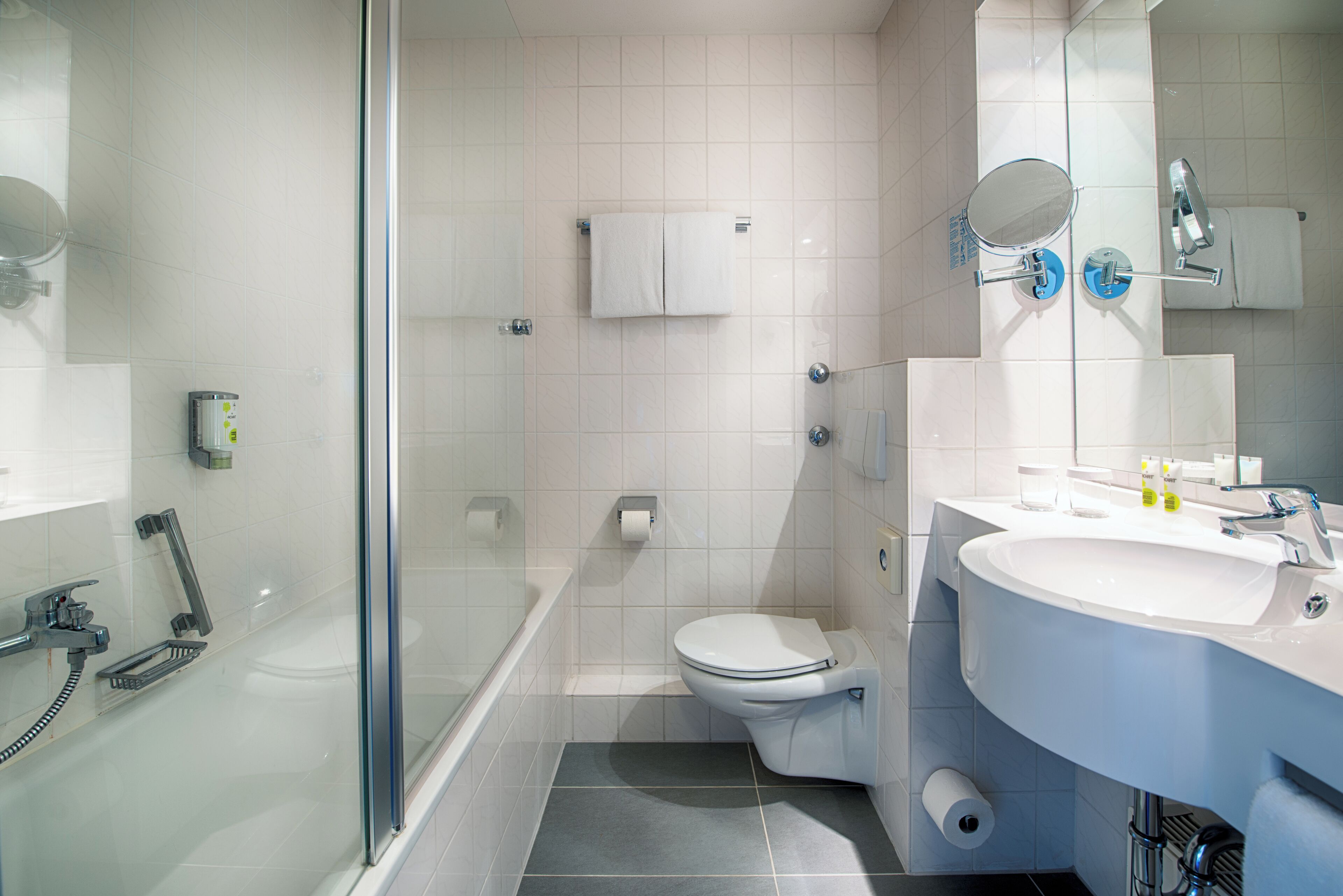 Een moderne badkamer met een douchecabine van glas, een toilet en een wastafel met spiegel.