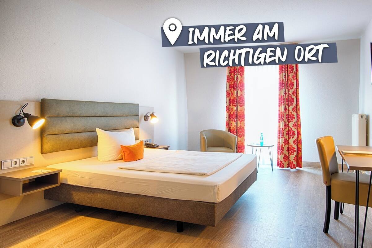 Une chambre d’hôtel comprenant un lit, des tables de chevet, une chaise, une petite table et un bureau.