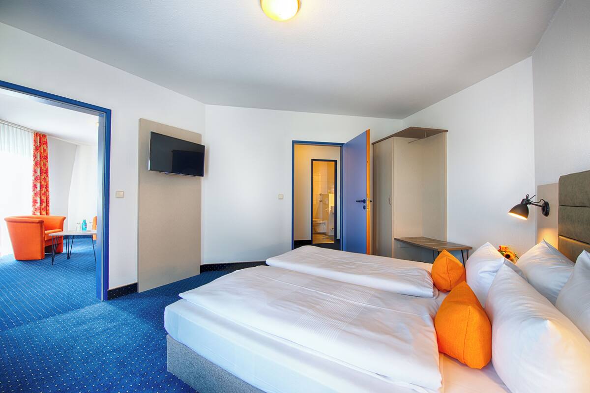 Une chambre d’hôtel avec un grand lit, un bureau, une chaise et un téléviseur fixé au mur.
