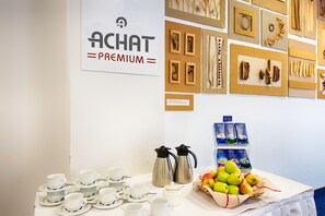 A table with white cups and saucers, two coffee makers, and a basket of apples. - ACHAT Hotel Zwickau (Zwickau)