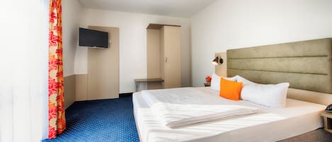 A hotel room with a large bed, a television mounted on the wall, and a blue carpet.