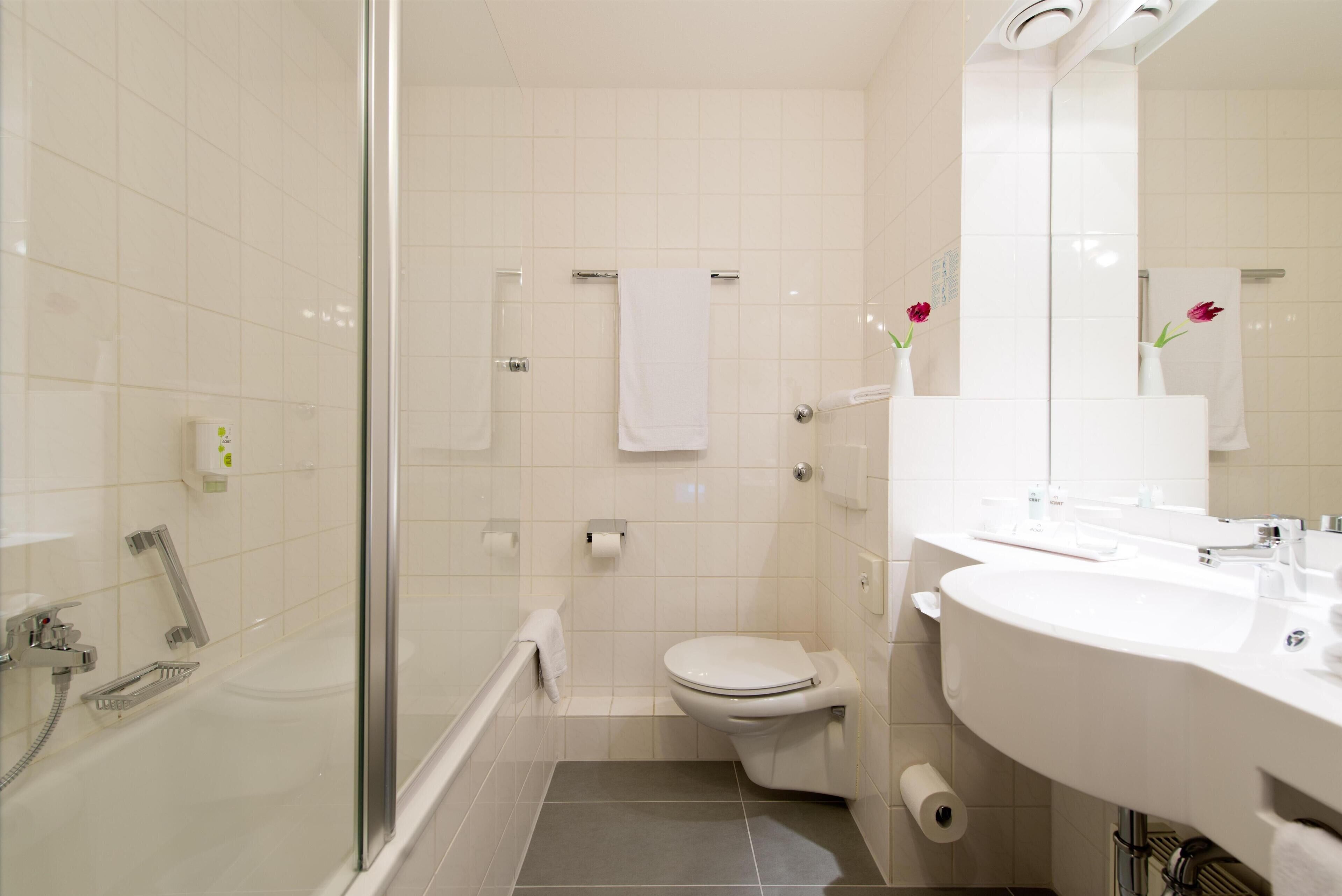 Ein modernes Badezimmer mit Duschkabine aus Glas, einer weißen Toilette und einem Waschbecken mit Spiegel.