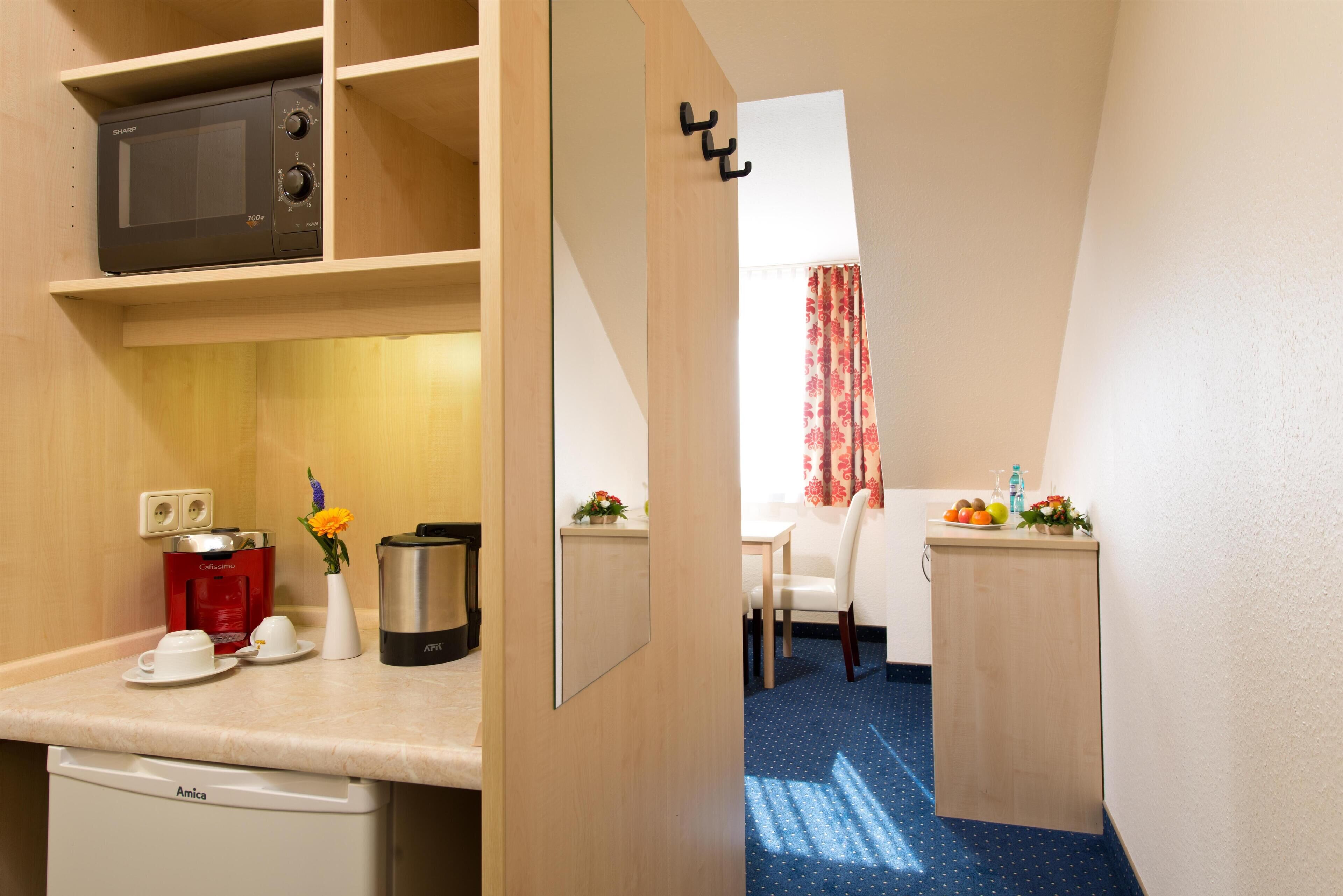 A compact kitchenette with a microwave, coffee maker, and a small sink.