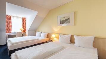 Une chambre d’hôtel avec deux lits, un bureau, une chaise et une lampe.