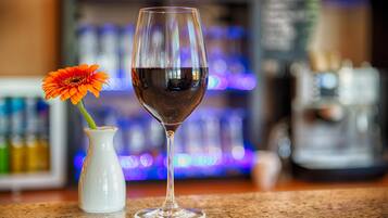 Ein Glas Rotwein und eine Vase mit einer einzelnen orangefarbenen Blume auf einer Theke.