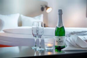 A hotel room with a bed, two wine glasses, a candle, and a bottle of champagne. - ACHAT Hotel Chemnitz (Chemnitz)