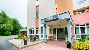 A hotel entrance with a sign reading "ACHAT HOTEL," outdoor seating, and potted plants. - ACHAT Hotel Chemnitz (Chemnitz)