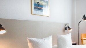 A hotel room with a bed, two bedside lamps, a nightstand, a desk, and a framed picture on the wall. - ACHAT Hotel Chemnitz (Chemnitz)