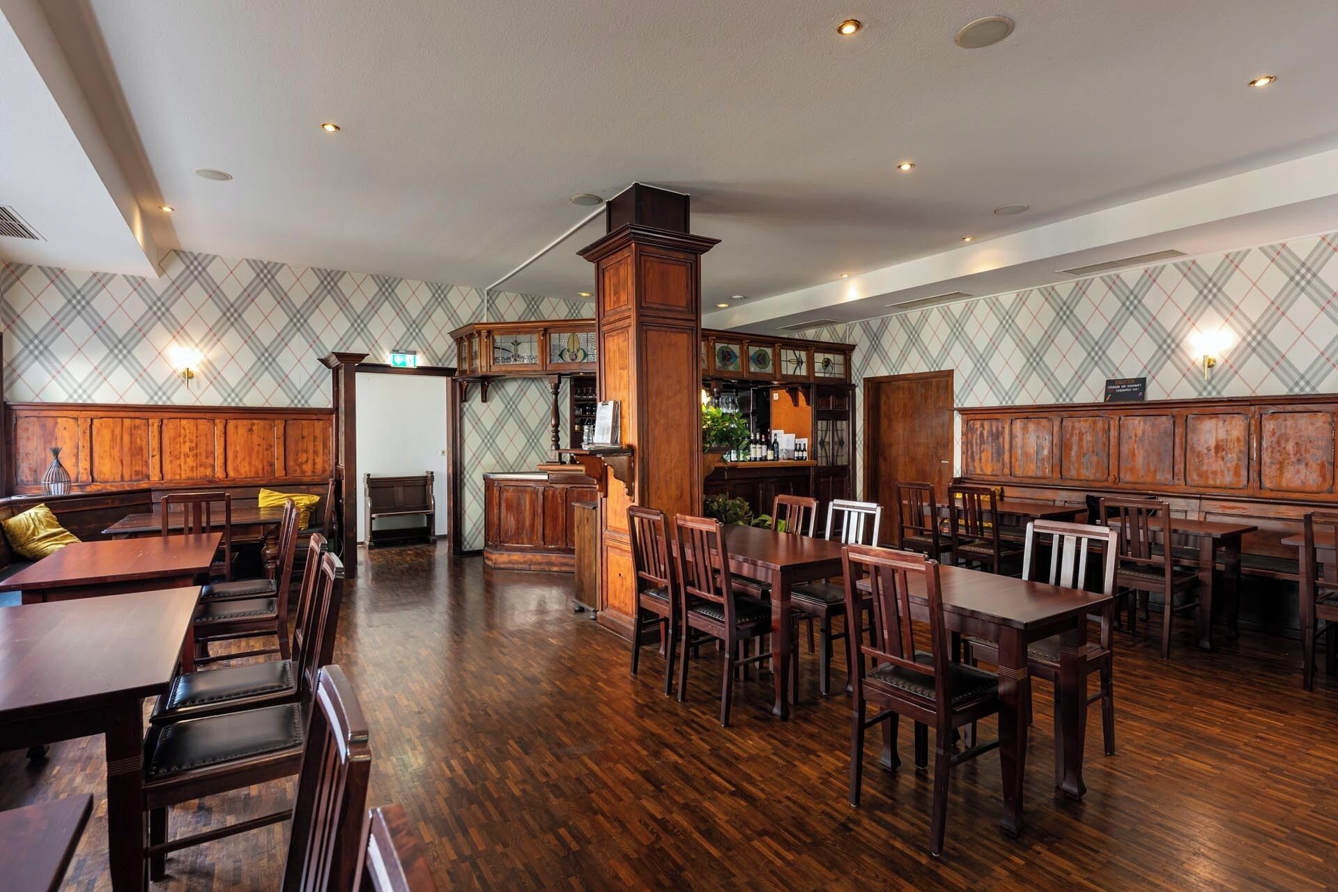 A spacious restaurant with wooden furniture and a checkered wall pattern.