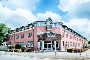 A multi-story building with a prominent entrance, large windows, and a clear sky. - ACHAT Hotel Schwetzingen Heidelberg (Schwetzingen)