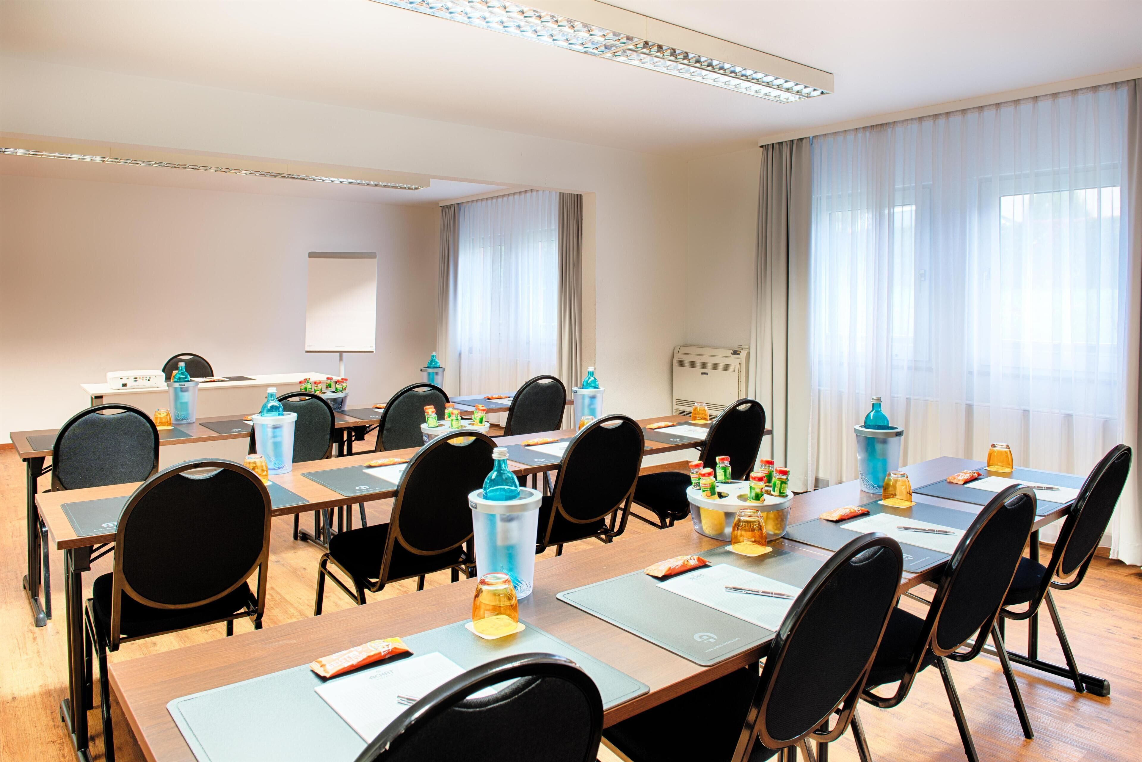 A conference room with multiple tables, chairs, and a projector screen.