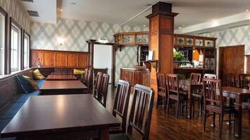 Un restaurante con mesas y sillas de madera, una zona de bar y una pared con diseño.