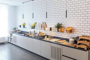 Una cocina moderna con azulejos blancos tipo metro, una encimera amplia con diversos alimentos y una tabla de cortar de madera.