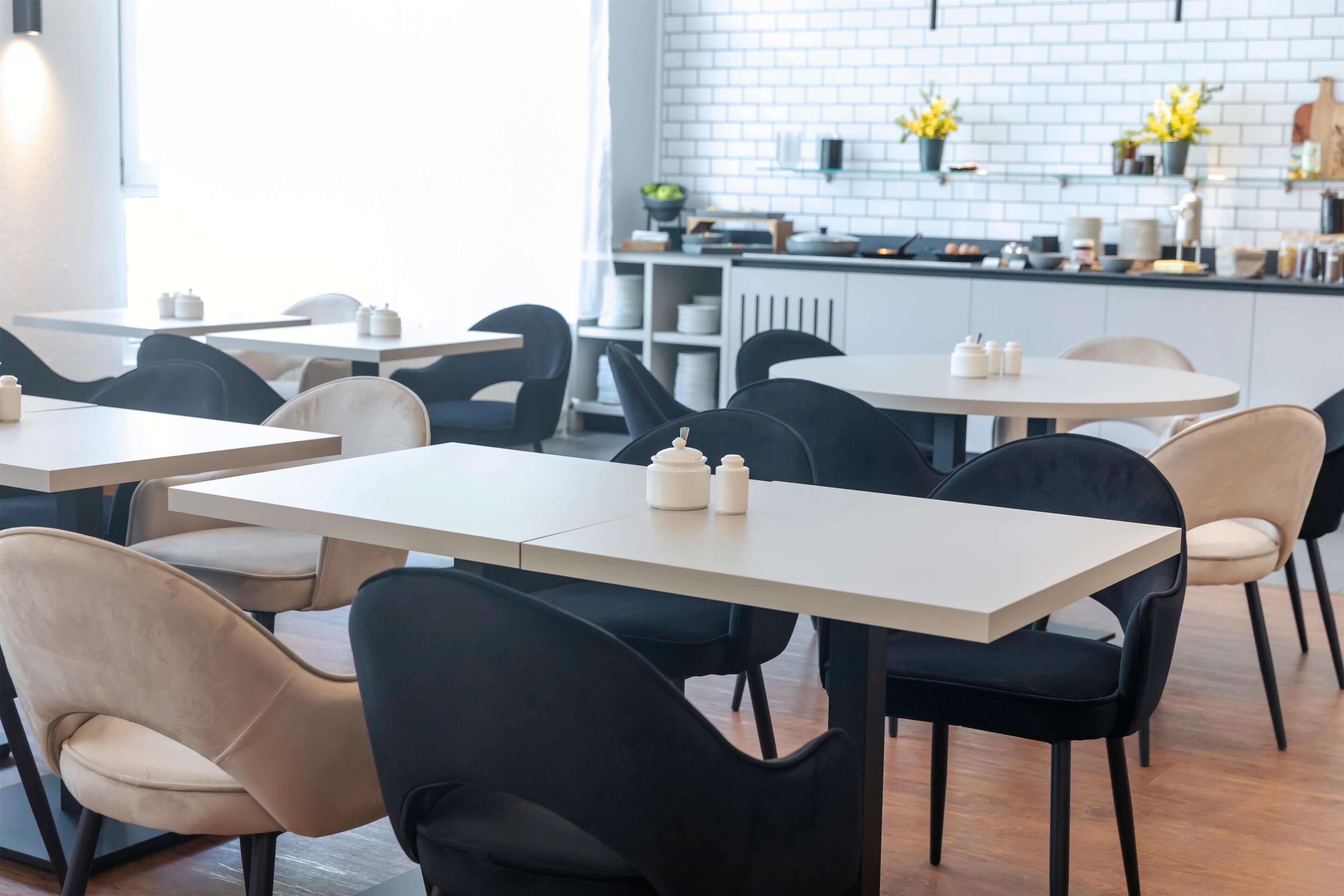 Un comedor moderno con mesas redondas y sillas negras y beige.