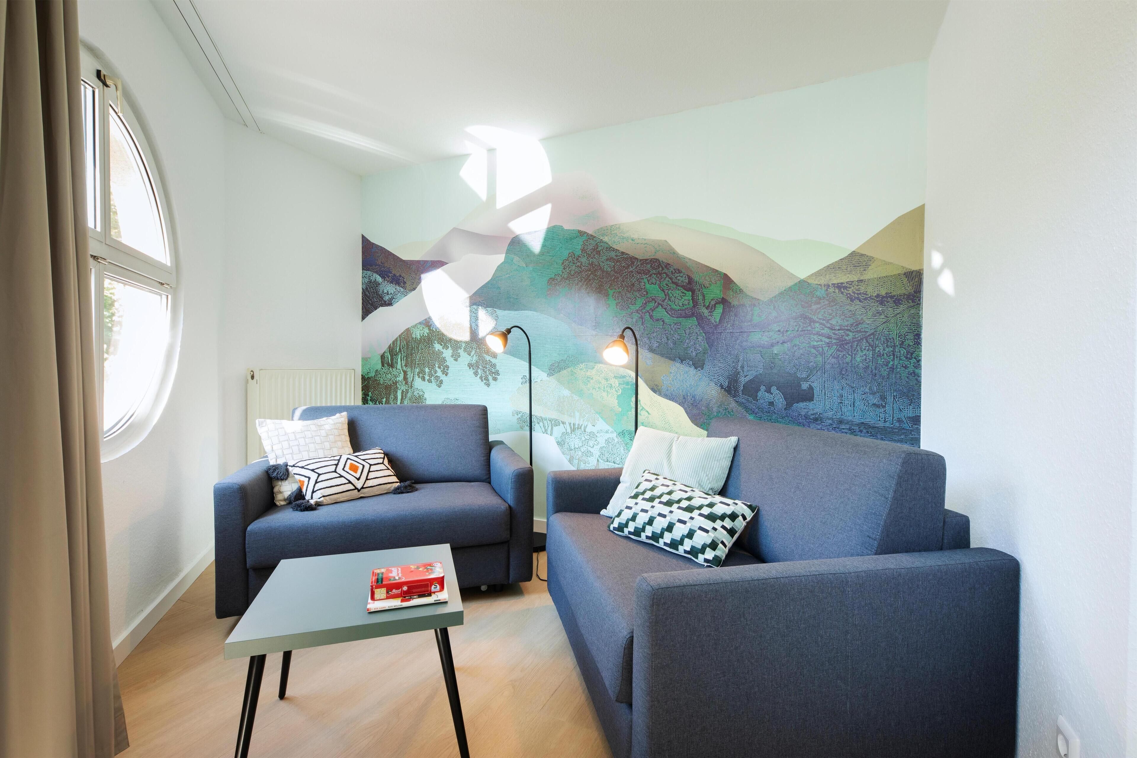 A modern living room with two sofas, a coffee table, and a large abstract painting on the wall.