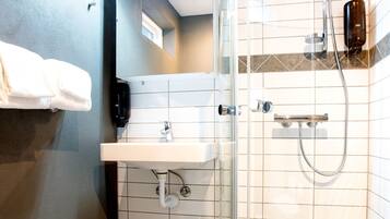Une salle de bain moderne avec une douche à parois de verre, un lavabo blanc et des toilettes.