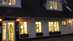 Un bâtiment avec de nombreuses fenêtres et portes illuminées, ce qui laisse supposer qu’il s’agit d’un hôtel ou d’un établissement d’hébergement similaire.
