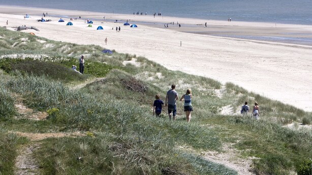 Une plage avec des tentes et des gens qui se promènent le long du rivage.